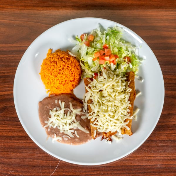 A plate of Mexican food with rice, refried beans, and a cheesy enchilada, topped with lettuce and tomatoes.