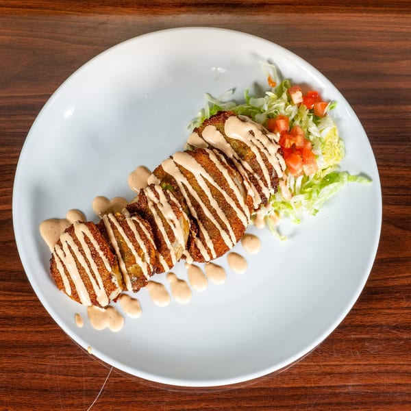 Crispy fried Mexican fritters drizzled with creamy sauce, served with shredded lettuce and diced tomatoes.