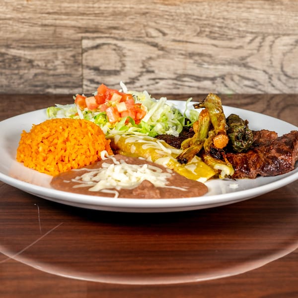 A Mexican combination plate with rice, refried beans, enchiladas, grilled steak, and charred peppers.