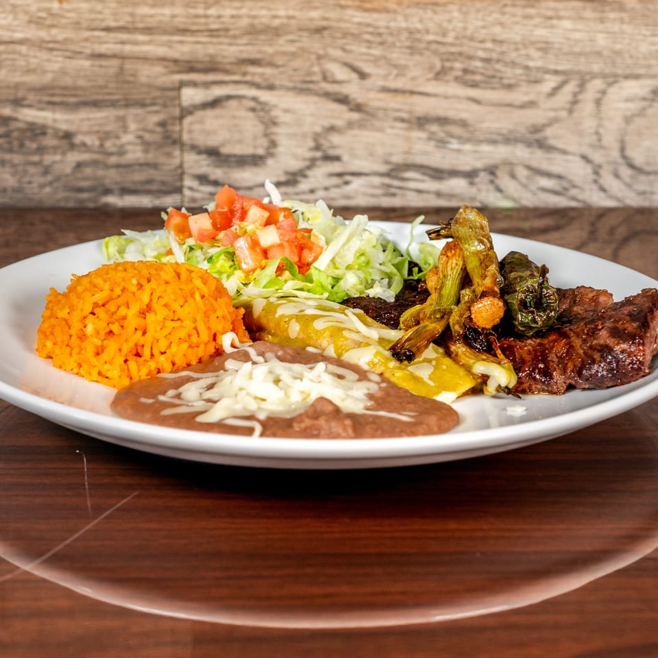 A Mexican combination plate with rice, refried beans, enchiladas, grilled steak, and charred peppers.